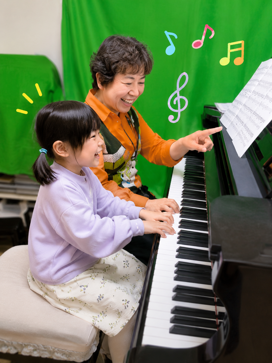 笑顔でピアノレッスンを受ける女の子と優しく指導する先生